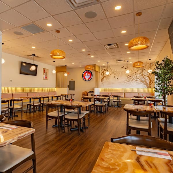 Shinjiru Ramen dining room with wooden tables, chairs, booth seating, and a tree mural.
