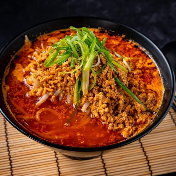 Shinjiru Ramen's spicy ramen bowl, topped with ground meat and fresh green onions, on a bamboo mat.