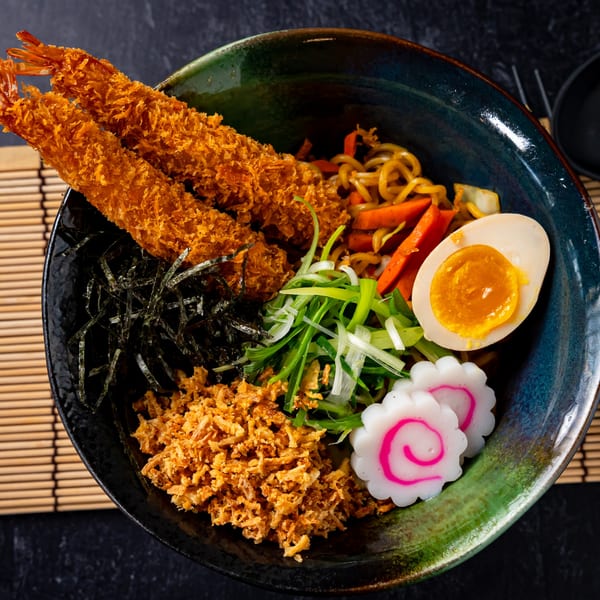 Shinjiru Ramen bowl with crispy fried shrimp, noodles, soft-boiled egg, scallions, and fish cake.