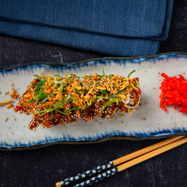 Shinjiru Ramen's crispy eel sushi roll with sauce, sesame seeds, scallions, and red ginger.