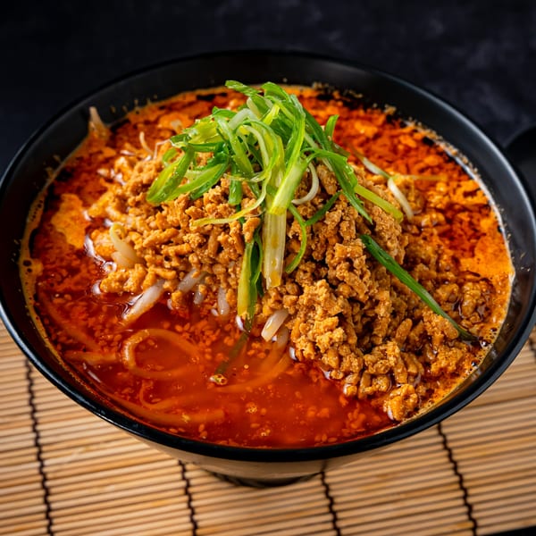 Shinjiru Ramen's spicy ramen bowl with ground meat, green onions, and bean sprouts on a bamboo mat.