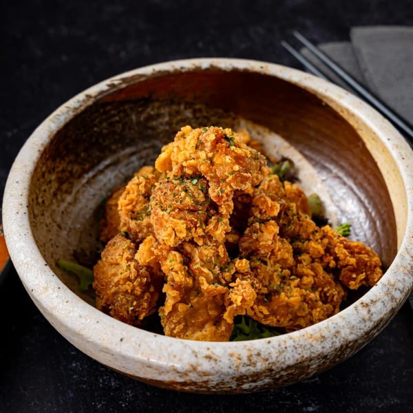 Crispy fried chicken pieces, seasoned with herbs, served in a rustic ceramic bowl at Shinjiru Ramen.