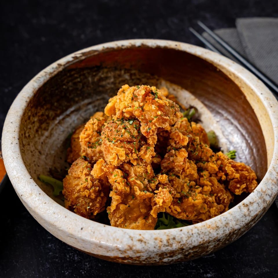 Crispy fried chicken pieces, seasoned with herbs, served in a rustic ceramic bowl at Shinjiru Ramen.