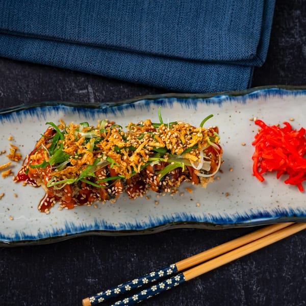 Shinjiru Ramen's crispy eel sushi roll with sauce, sesame seeds, scallions, and fried onions.