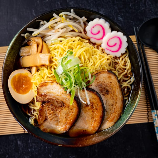 A bowl of Shinjiru Ramen with noodles, pork, egg, bamboo shoots, bean sprouts, and narutomaki.