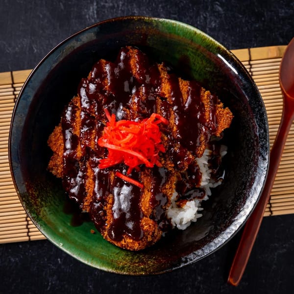 A Shinjiru Ramen tonkatsu donburi bowl with crispy pork cutlet, dark sauce, and red pickled ginger.