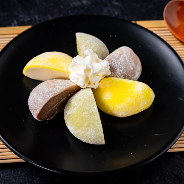 Assorted mochi ice cream with whipped cream on a black plate at Shinjiru Ramen.