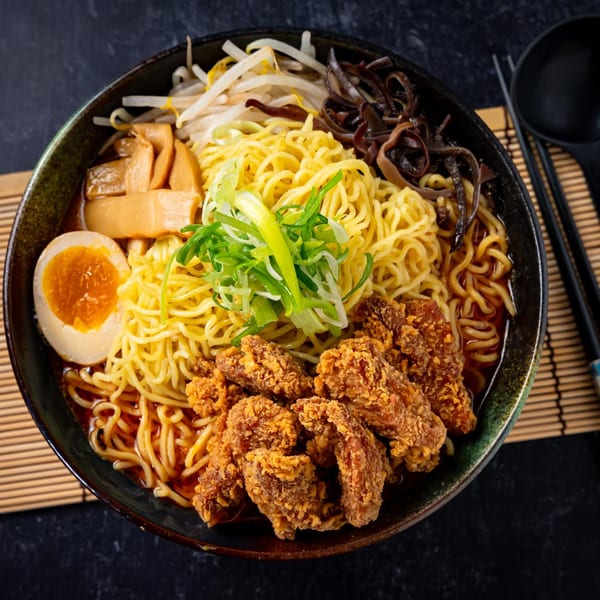A bowl of Shinjiru Ramen with fried chicken, egg, bamboo shoots, bean sprouts, and scallions.